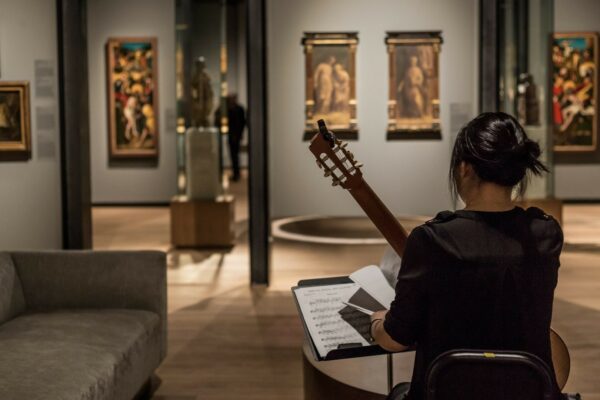 Someone playing an acoustic instrument in an art gallery, reading sheet music