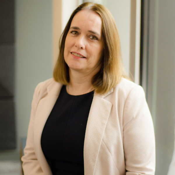 Christine Keeley, a middle aged woman with shoulder length light brown hair, wearing a cream suit jacket and black top.