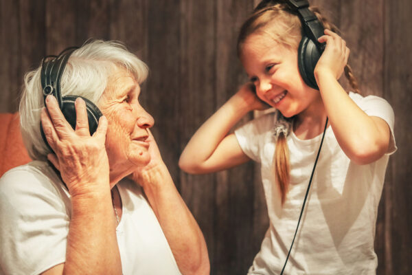 old woman and little girl in headphones listening to music