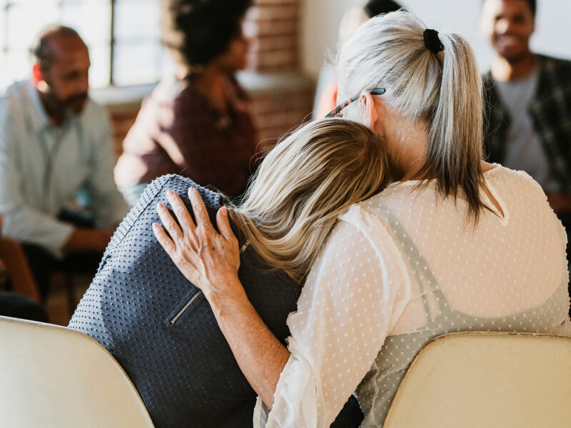 Two women support each other in a rehab session