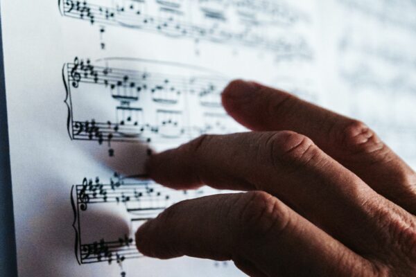A hand touching and pointing at sheet music