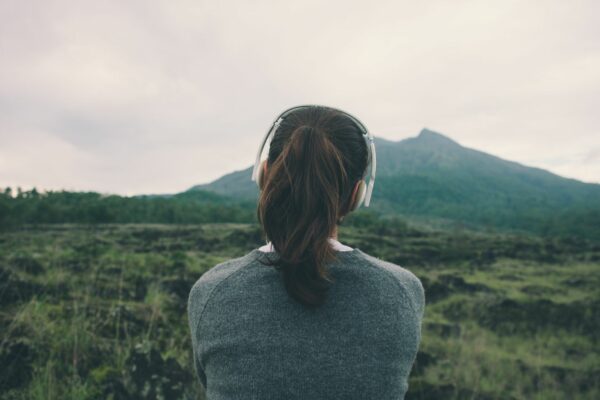 A woman with brown hair in a ponytail looking away from the camera at a green landscape