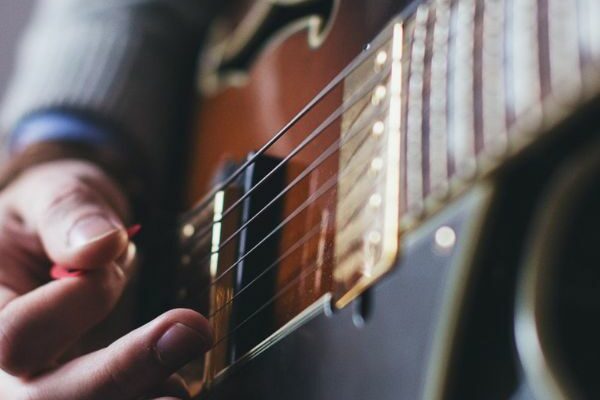 A close up of someone playing a dark brown and black guitar