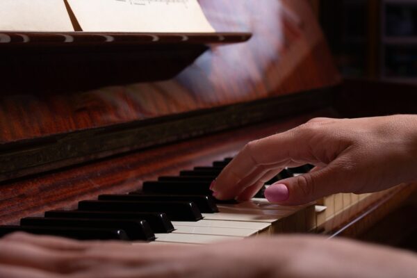 hands with pink nail varnish playing a piano