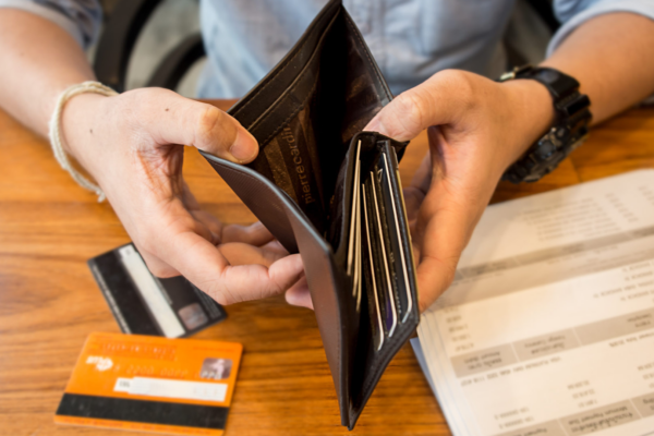 A person opening an empty wallet with credit cards on the table below